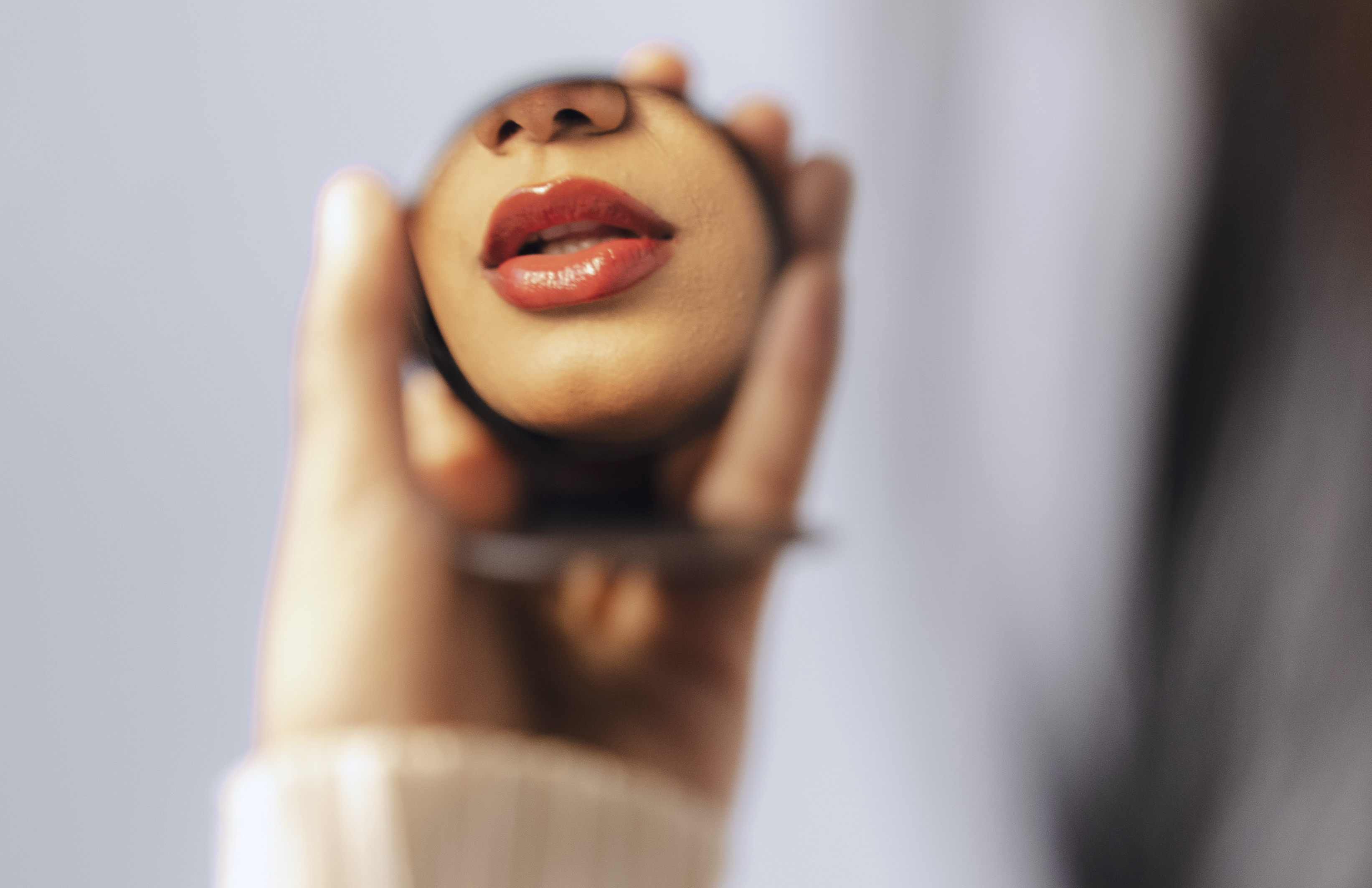 Woman checking her lips in a compact mirror after lip filler treatment