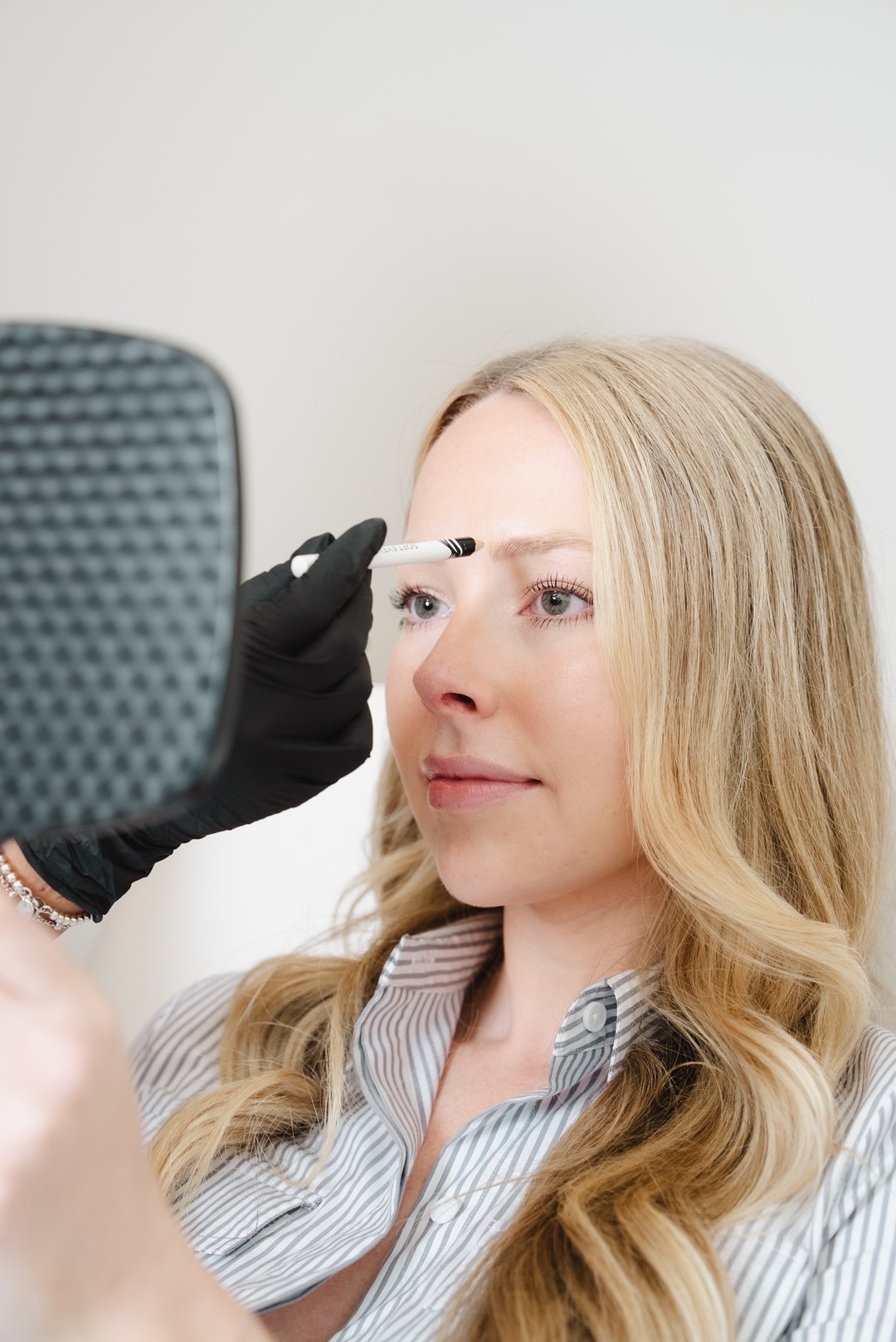 A Be Your Kind provider mapping a client's brow during a treatment consultation